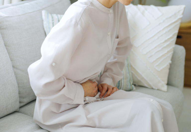 腹痛のため下腹部をおさえる女性